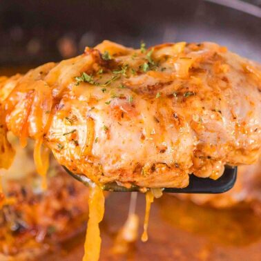 A close-up of a cooked, saucy chicken breast being lifted from a pan with a spatula—perfect for easy recipes and quick 1-pot meals.
