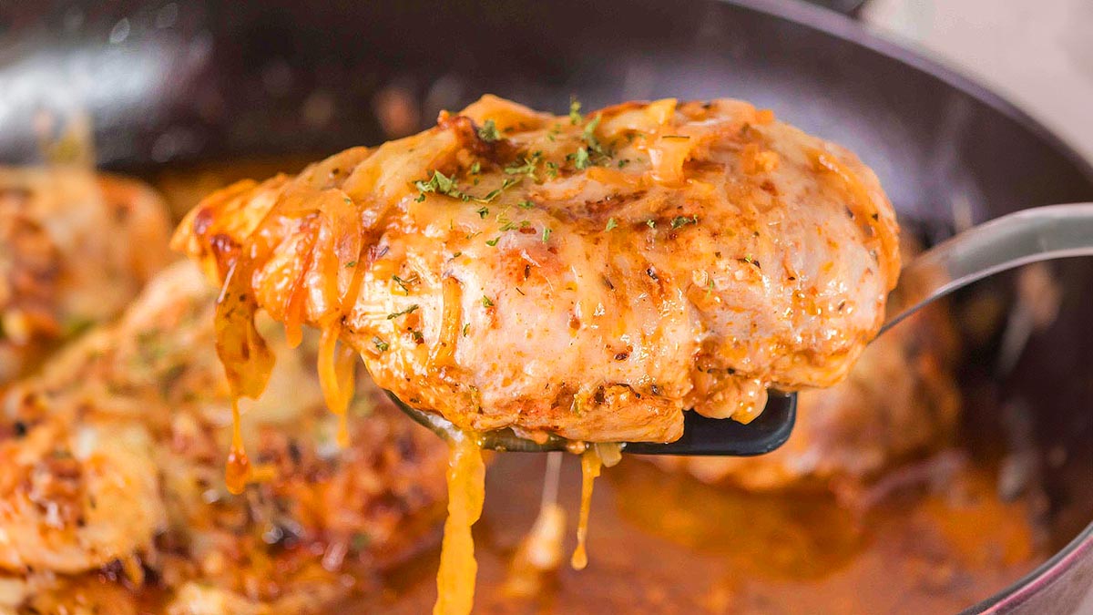 A close-up of a cooked, saucy chicken breast being lifted from a pan with a spatula—perfect for easy recipes and quick 1-pot meals.