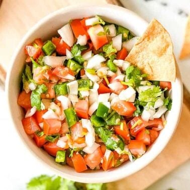 A bowl of fresh pico de gallo with diced tomatoes, onions, jalapeños, and cilantro, garnished with tortilla chips on the side—perfect for easy recipes and quick meals.