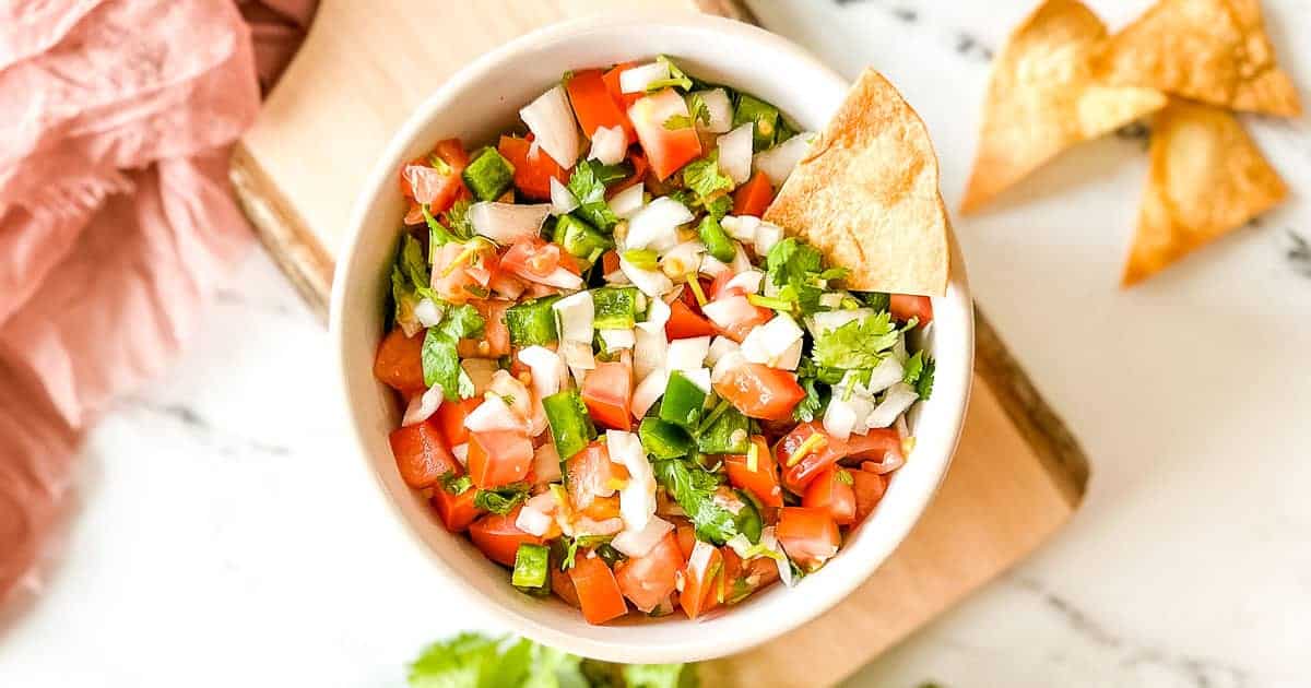 A bowl of fresh pico de gallo with diced tomatoes, onions, jalapeños, and cilantro, garnished with tortilla chips on the side—perfect for easy recipes and quick meals.