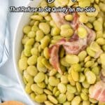 A bowl of cooked lima beans with pieces of bacon, shown close up on a table with a striped cloth and wooden spoon nearby.