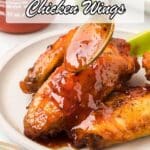 A spoon drizzling sauce over cooked chicken wings on a plate, with lime wedges on the side and text promoting chicken wing flavor ideas.