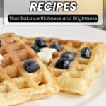 Two golden waffles topped with blueberries and a dollop of butter on a white plate, with a glass of orange juice in the background. Text overlay reads "12 Buttermilk Recipes.