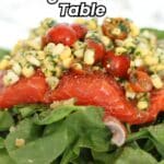 A piece of cooked fish topped with a corn and tomato salsa, served on a bed of fresh spinach leaves. Text overlay reads: "Bring Fish to the Table.