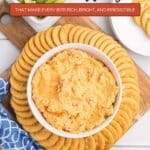 A bowl of cheese spread is surrounded by round crackers on a wooden board, with sliced vegetables and more crackers on the side. Text reads, "13 Cheese Appetizers.