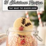 A glass jar decorated with candy cane designs is filled with reindeer-shaped Christmas cookies; the lid is open, and milk with candy cane straws is in the background.