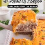 A close-up of a cheesy meatloaf topped with mashed potatoes being served from a casserole dish, with text overlay: โ15 Meatloaf Recipes That Go Beyond the Basics.โ.