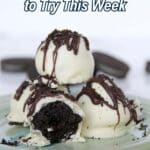 A plate of chocolate truffles coated in white chocolate and drizzled with dark chocolate, with one truffle bitten to show the inside.