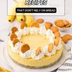 A banana cheesecake topped with whipped cream and vanilla wafers sits on a table with bananas, cookies, and a striped napkin nearby. Text overlay reads "20 Banana Dessert Recipes That Don't Rely on Bread.