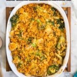 A baked casserole topped with crushed crackers sits in a white oval dish on a wooden board, surrounded by a spoon and a patterned napkin. Text overlay reads “21 Southern Recipes.”.