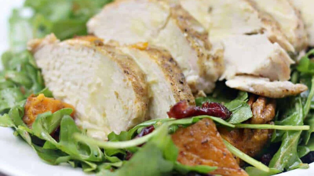 Sliced cooked chicken breast served on a bed of mixed greens with roasted sweet potatoes and dried cranberries—one of our flavorful recipes perfect for easy cooking.