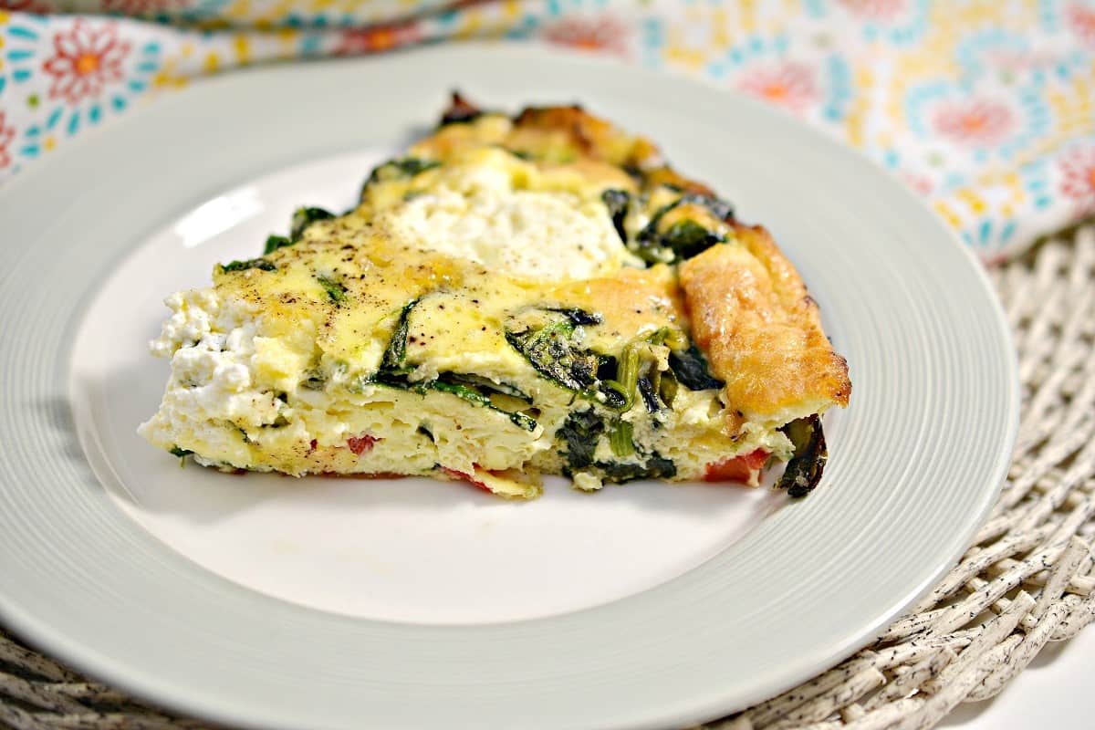 A slice of simple vegetable frittata with spinach and cheese is served on a white plate—a delicious option for easy breakfast recipes.