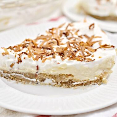 A slice of cream pie topped with toasted coconut flakes on a white plate—perfect for anyone who loves bold baking and irresistible desserts.