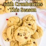 A plate of cookies with cranberries is on a white surface, accompanied by a pink striped towel. Text reads: "17 Ways to Bake with Cranberries This Season.