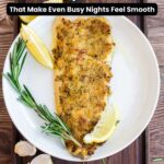 A seasoned baked chicken breast is served on a white plate with lemon wedges, garlic cloves, and rosemary sprigsโperfect for easy dinners on busy nights.