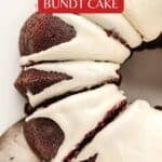 A sliced red velvet bundt cake with white icing, served on a plate with a metal cake server.