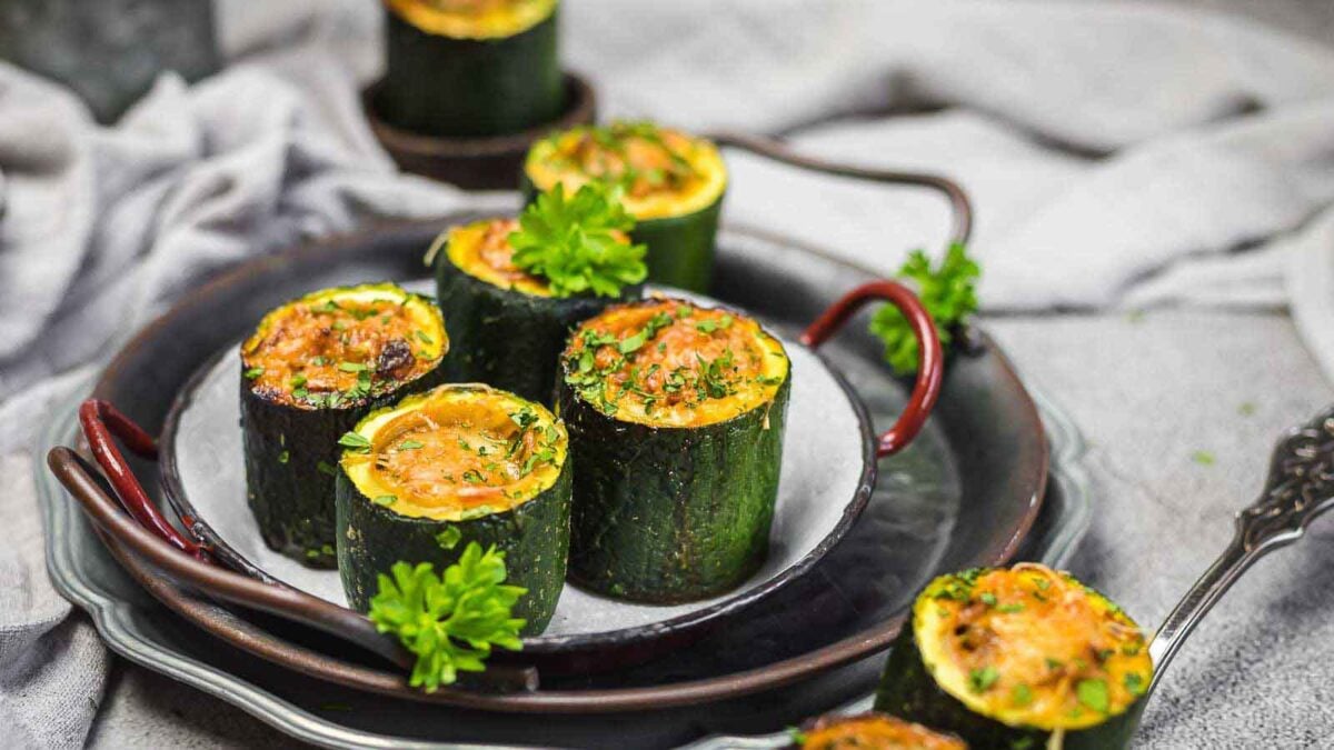 Several zucchini rounds, hollowed and stuffed with a baked filling, are garnished with fresh parsley and arranged on a plate—an inviting addition to any collection of zucchini recipes.