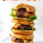 A stack of three cheeseburgers with lettuce, tomato, bacon, and beef patties on sesame seed buns, with text about Blackstone recipes at the top.