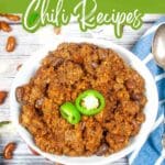 A bowl of chili with beans, topped with sliced jalapeรฑos, sits on a table with a spoon beside it. Text above reads, "13 Big, Slow-Built Comfort Poured Into Every Chili Recipe.