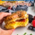 A hand holds a partially eaten breakfast slider with egg and bacon on a plate, alongside berries and herbs. Text overlay reads, "13 Sliders Packed with Bite-Sized Layers of Juicy Goodness.
