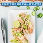 A plate with three shrimp tacos garnished with lime wedges and sliced jalapeรฑos sits next to metal tongs; text above reads "14 Shrimp Recipes Ready Fast and Full of Flavor.