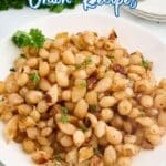 A white bowl filled with cooked pearl onions garnished with chopped parsley, placed on a white surface with a sprig of parsley nearby.