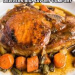 A plate of roasted pork chop served with carrots, green beans, and potatoes in savory brown gravyโan irresistible pork dinner sure to deliver savory comfort.