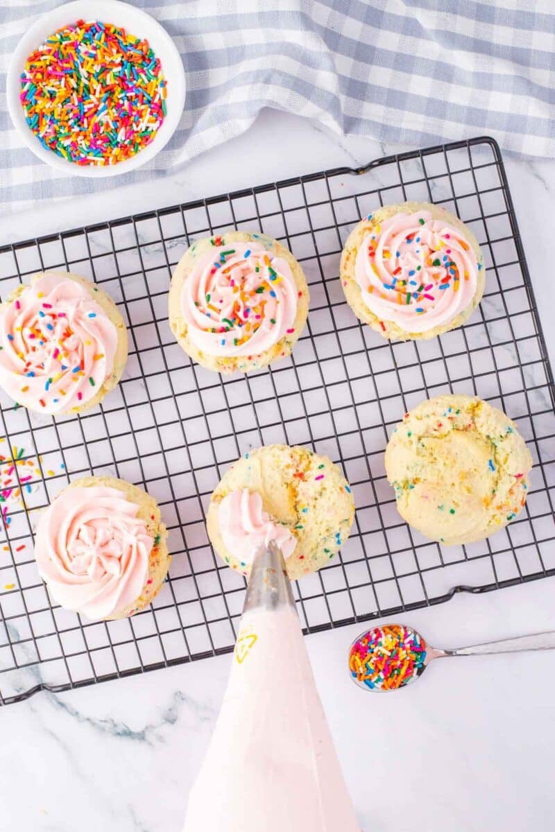 A baking tray with cupcakes and sprinkles.