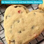 A heart-shaped cookie with chocolate chips and red candy pieces on a cooling rack, overlaid with text about 13 Valentine recipes.