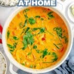 A pot of orange curry garnished with cilantro sits on a white surface, surrounded by bowls of rice. Text overlay reads, "Curry Recipes at Home.