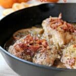 A cast iron skillet filled with crispy, cooked chicken pieces topped with bacon. Text above reads: "15 Crunch First, Flavor Next, That’s the Magic of Crispy Recipes.
