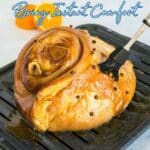 A glazed ham studded with cloves is being brushed with sauce on a grill pan. Text overlay reads, "Ham Recipes Bring Instant Comfort.