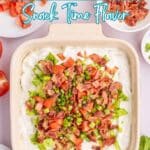 Square dish filled with creamy dip, topped with chopped lettuce, bacon, tomato, and green onions; diced tomatoes and green onions in small bowls nearby. Text overlay reads โ19 dips.โ.