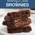 A stack of three chocolate brownies on a white plate, with text reading “Hershey’s Cocoa Brownies” above and “Save for later!” below.