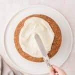 A person spreading frosting on a cake.