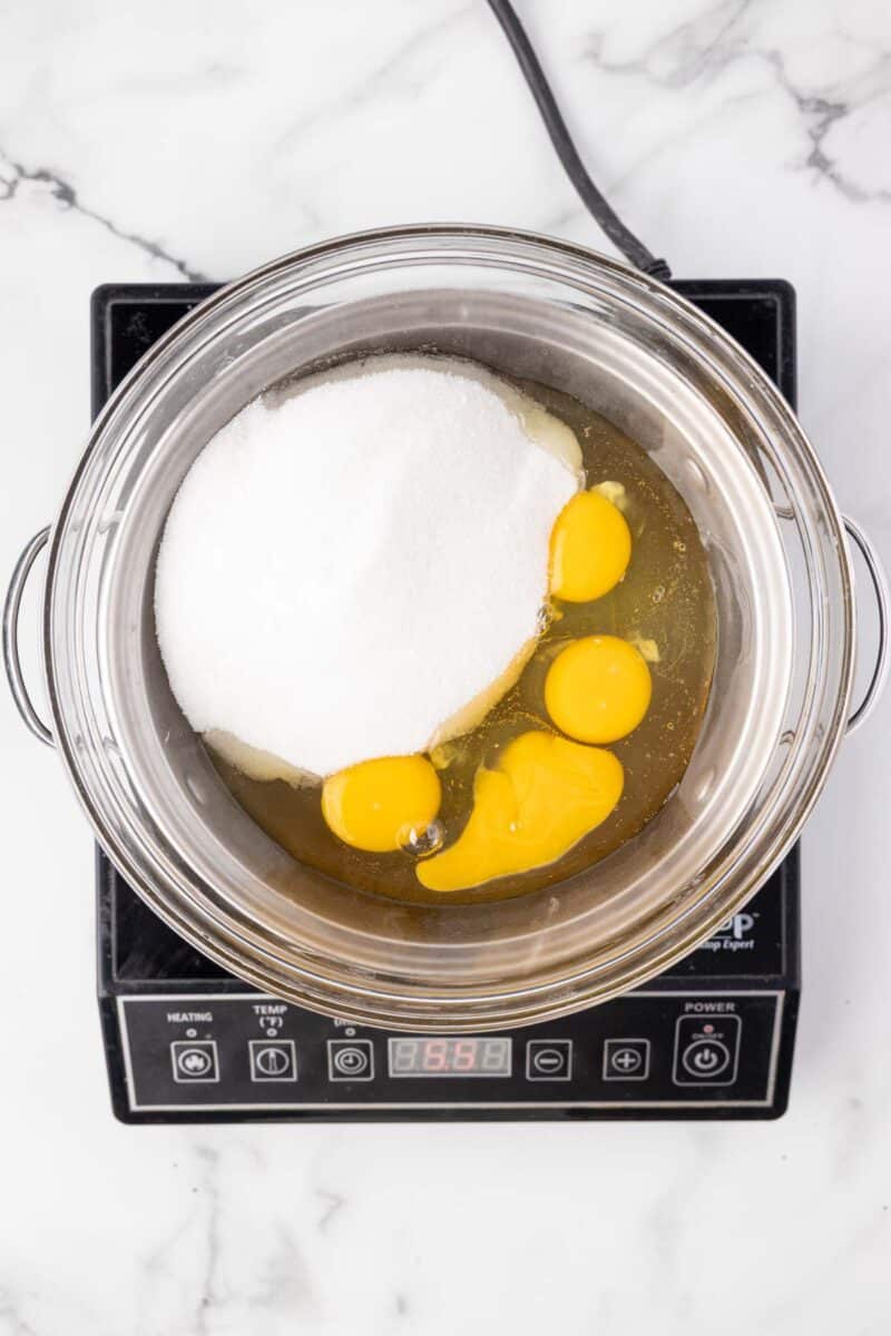 A bowl of eggs and sugar on a stove.