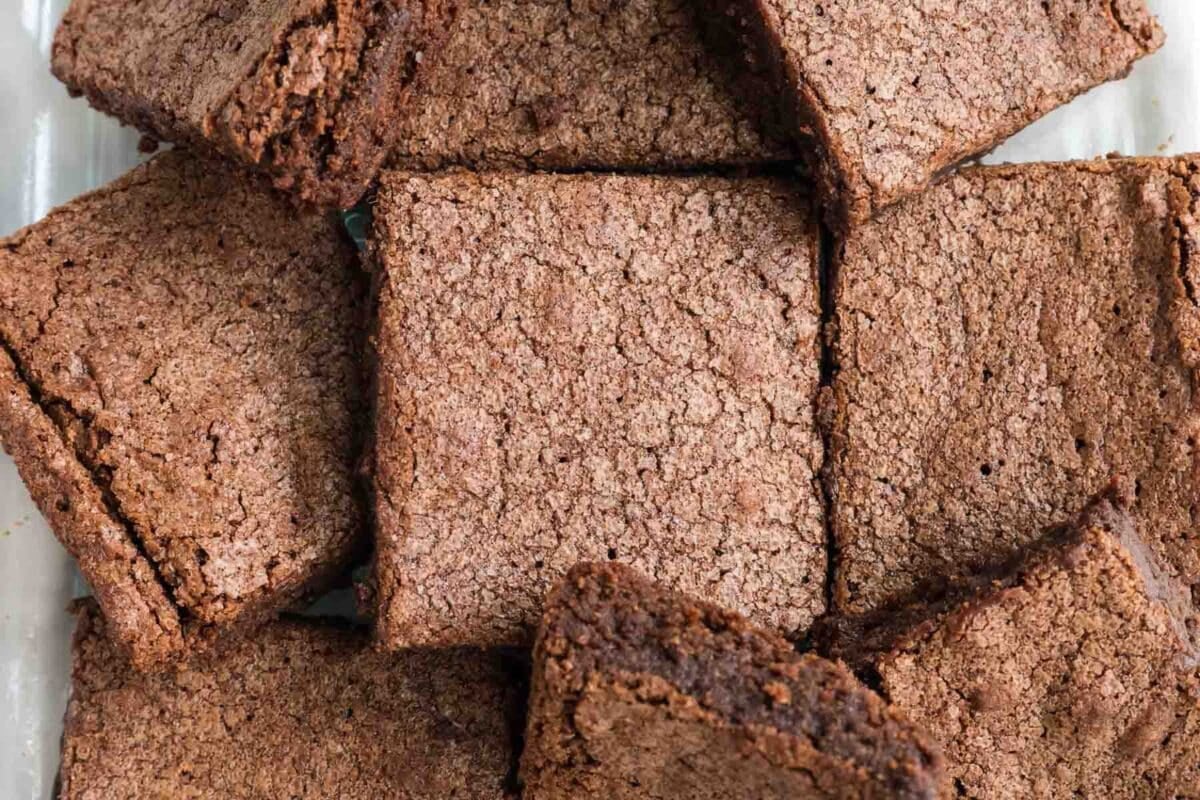 A close-up view of several chocolate brownies arranged in a pile, with one brownie in the center surrounded by others.