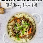 A bowl of savory beef and vegetables served over rice, garnished with green onions and sesame seeds, with chopsticks and a piece of ginger nearbyโperfect for fans of skillet beef recipes.