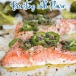 Close-up of baked salmon fillets topped with capers and sliced jalapeรฑos, surrounded by roasted broccoli on a sheet pan. Text overlay reads "12 Oven-Baked Seafood Dinners.
