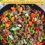 A skillet filled with cooked ground beef, sliced mushrooms, bell peppers, carrots, and green onions, topped with sesame seeds. Text overlay reads "13 Gluten-Free Beef Dinners"โeach recipe made with safe ingredients for a delicious beef dinner.