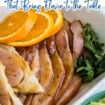 Sliced glazed ham garnished with orange slices and parsley, presented in a white dish, with bold ham recipes text featured at the top.