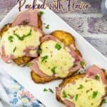 A white plate with three pieces of chicken topped with ham and melted cheese, garnished with herbs, sits on a rustic table next to a floral napkin. Text overlay is above the plate.