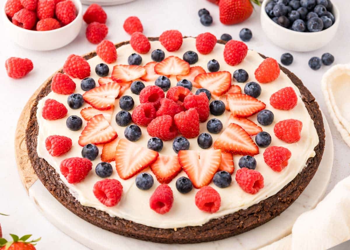 Fudgy brownie base topped with cream cheese frosting and fresh berries—the ultimate dessert pizza!