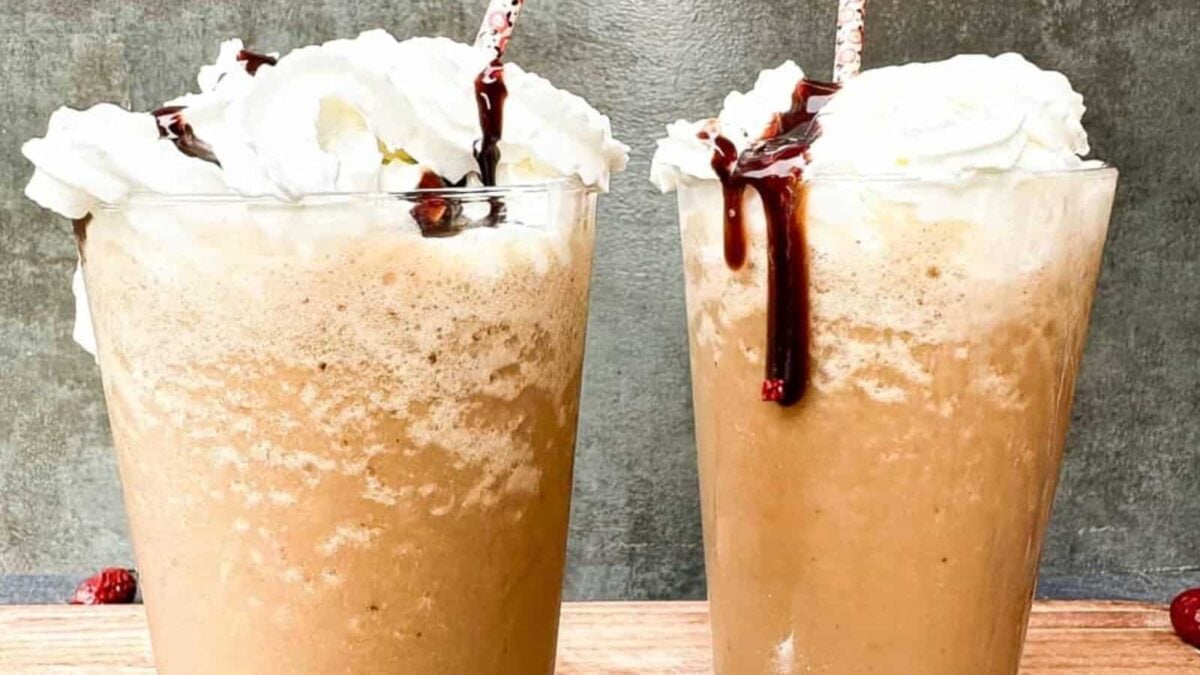 Two iced coffee drinks topped with whipped cream and chocolate syrup, each served in a clear glass with a straw—perfect for anyone seeking inspiring coffee ideas and bold coffee flavors.