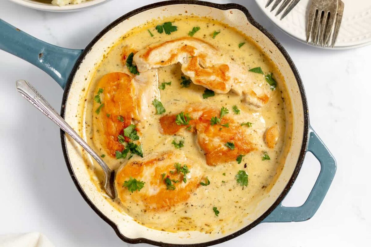 Chicken breast pieces in creamy herb sauce, garnished with chopped parsley, served in a blue-handled skillet with a spoon—a fresh take on Ranch recipes.
