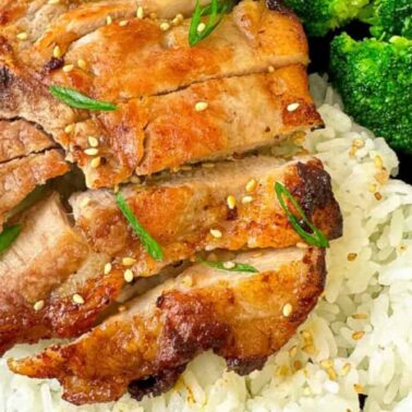 Grilled sliced pork served over white rice, garnished with sesame seeds and green onions, with steamed broccoli on the sideโ a high-protein meal bursting with fresh flavor.