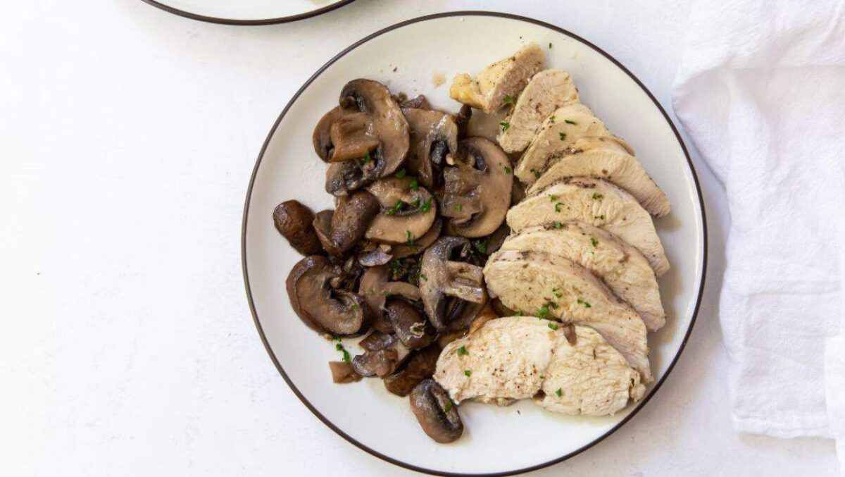 A plate with sliced cooked chicken breast and sautéed mushrooms, garnished with chopped herbs—an earthy and savory dish perfect for those who love mushroom recipes.
