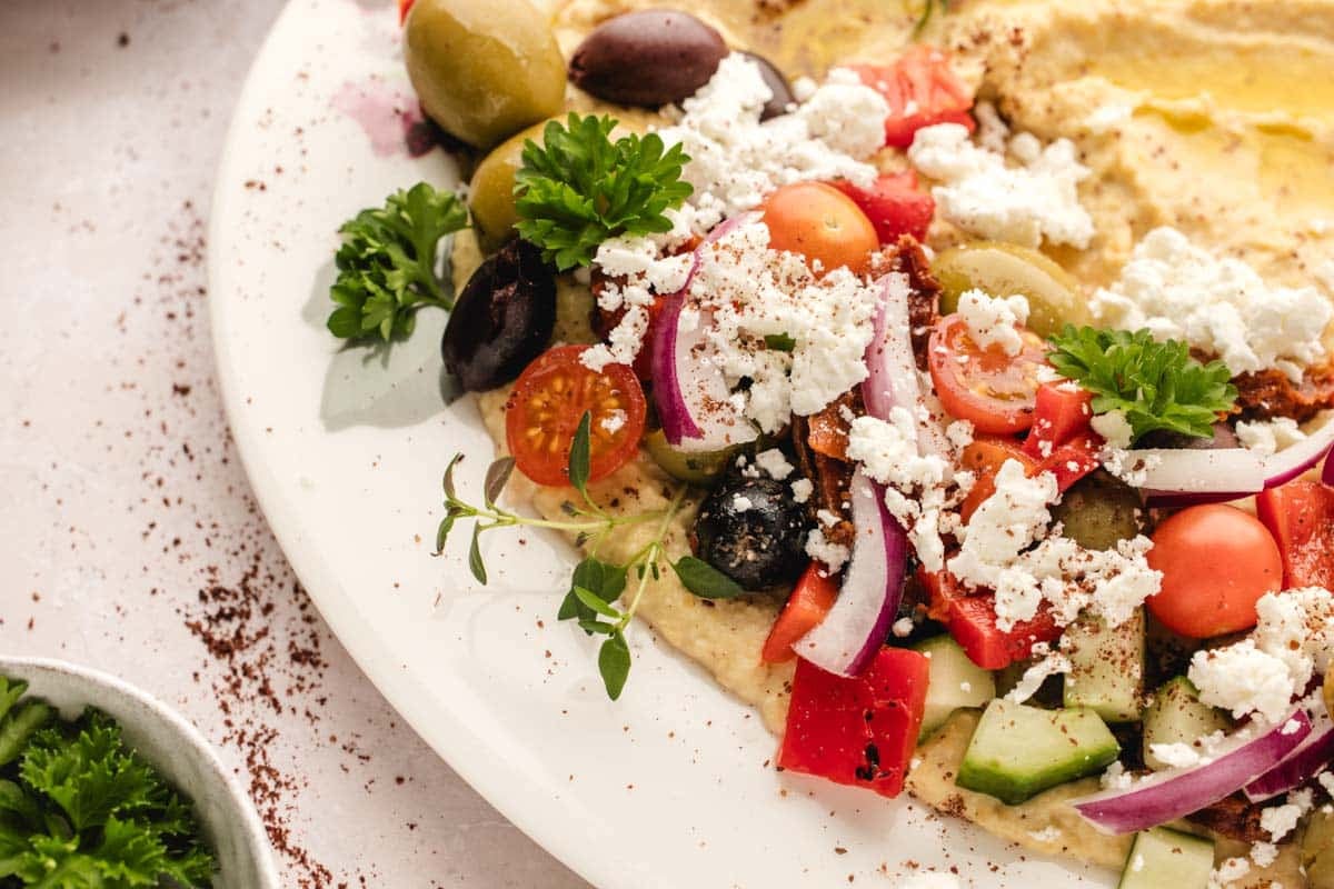 Creamy hummus piled high with fresh veggies, olives, and feta—perfect for snacking or entertaining.