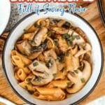 A bowl of penne pasta with mushrooms and herbs sits on a wooden surface, beneath text that reads "11 Mushroom Dinner Recipes Full of Savory Flavor.