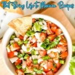 A bowl of fresh salsa with chopped tomatoes, onions, cilantro, and jalapeรฑos, garnished with a tortilla chip. Text above reads, "15 Vibrant Spices and Crunchy Toppings for Authentic Mexican Recipes.